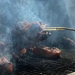 Meat smoking inside an offset smoker cooking chamber