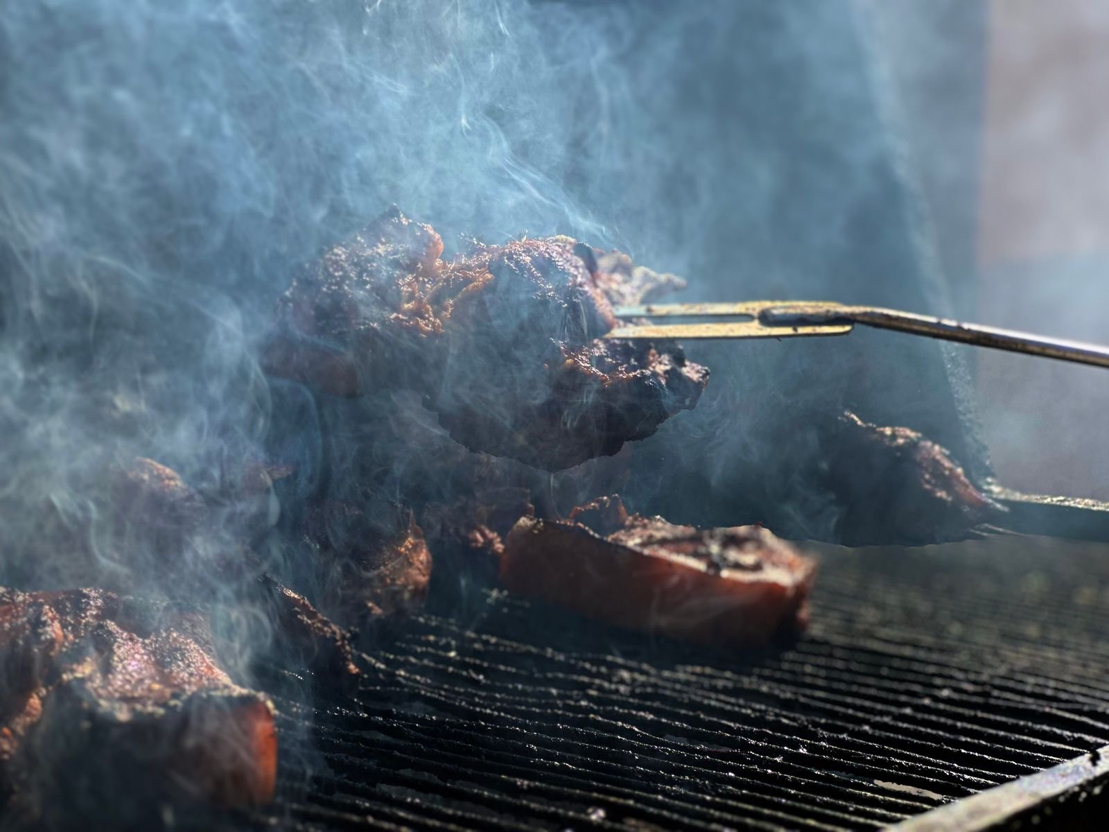 Meat smoking inside an offset smoker cooking chamber